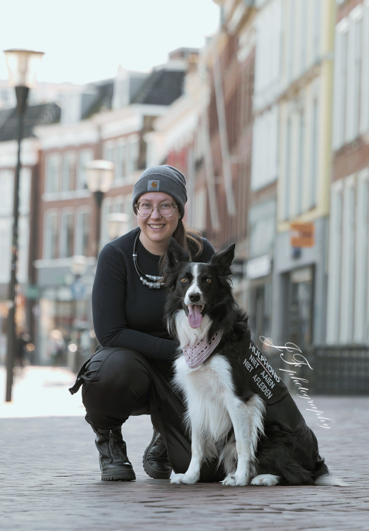 Larissa gehurkt naast haar border collie hulphond in de binnenstad